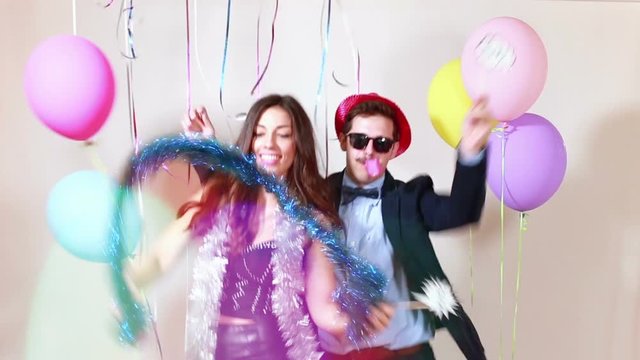 Funny crazy couple having awesome time dancing in party photo booth, graded in slow motion