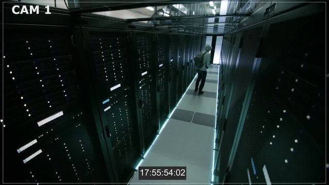 Security Camera N1 Footage of Hacker in a Hoodie Inflitrating Data Center, With His Laptop He Connects to One of The Rack Servers. Shot on RED EPIC-W 8K Helium Cinema Camera.