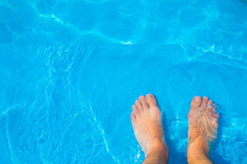 High angel view of feet on blue pool water