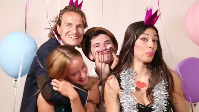 Two cute young couples having fun in party photo booth 