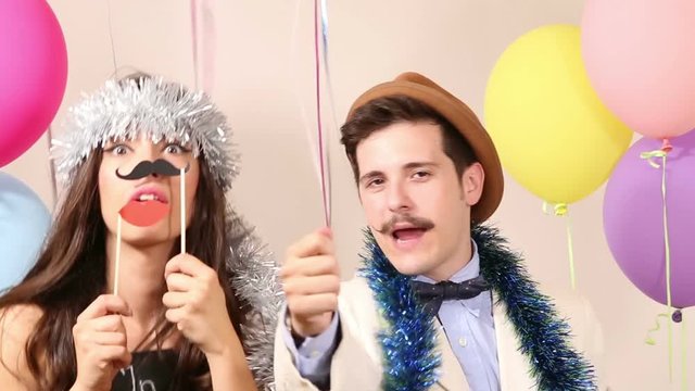 Slow motion of cute young couple having fun in party photo booth