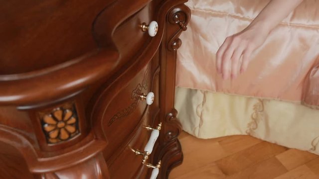 womans hand takes sex toys from the bedside table