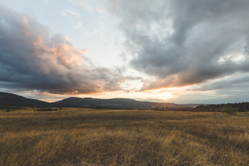 Cloudy Sunset Over Mountains and Field