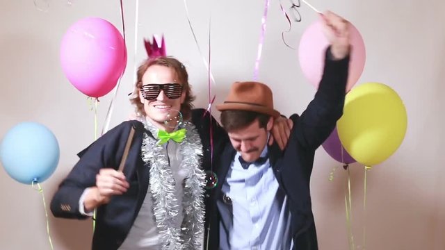 Two funny male friends having fun with props in photo booth