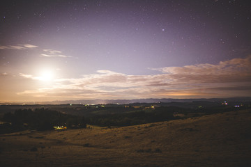 Fototapeta na wymiar Bright Moon in Night Sky Over Rural Farm Land