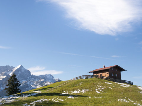 Holzhaus auf dem Eckbauer vor schneebedeckter Gipfelkulisse des Karwendels, Garmisch, Bayern