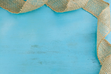 Jute ribbon  corner frame on blue wooden background with empty space