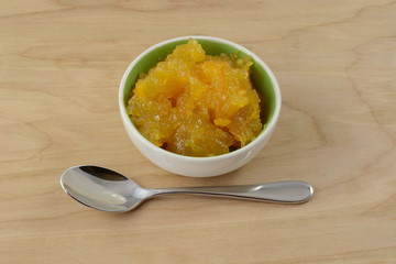 Orange marmalade in small condiment bowl on wooden table