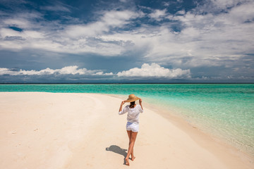Fototapeta na wymiar Woman with sun hat on tropical beach