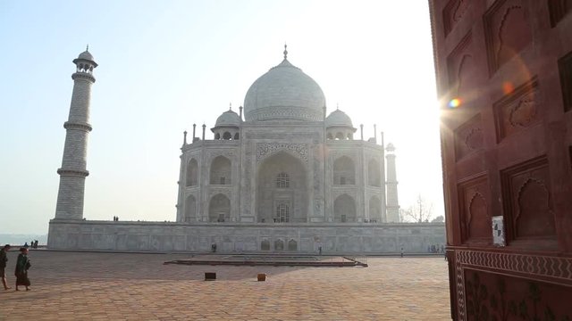 Taj Mahal front view, with people passing and blue sky in background.