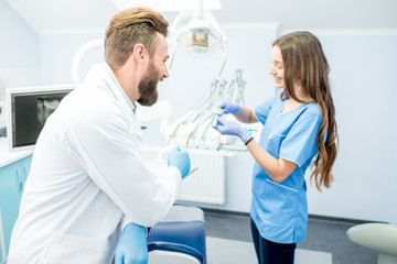 Handsome Dentist With Young Female Assistant In Uniform Prepairing