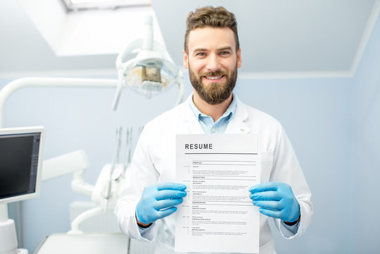 Professional Dentist Holding Resume For A New Job Standing At The Dental Office