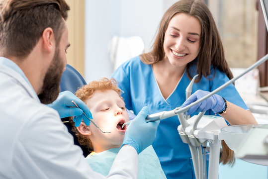 Young boy during the dental procedure with dentist and assistant at the dental office