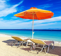 deck chairs and umbrella on background of sea and pebbles