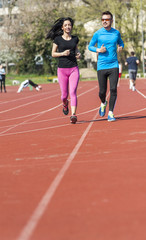 Fototapeta premium Young couple exercise running on the track