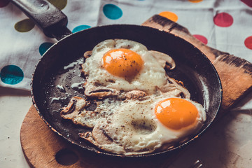 Two fried eggs with mushrooms in a pan