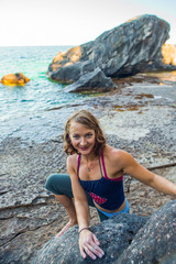 Beautiful woman boudering rock climbing on the shore