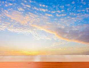 wooden tabletop with sunlight on the blue sky and clouds background.