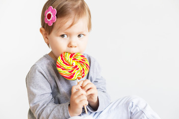 Small girl eating lollipop. Happy children with a big delicious candy.