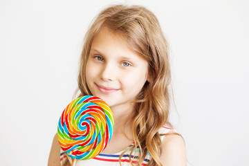 Fototapeta na wymiar lovely little girl with big delicious lollipop against a white background