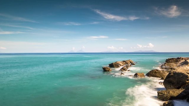 timelapse of a rocky beach and Mediterranean sea with the Aolien islands in the far distance, sicily, Italy.