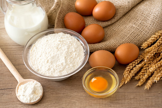 Eggs, flour and baking ingredients on a wooden table .