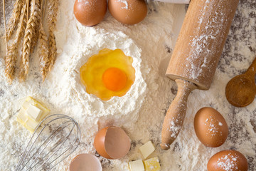 eggs, dough, flour and rolling-pin baking cakes on wooden table.