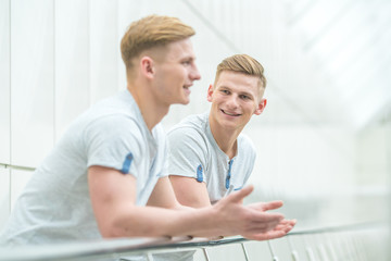 The two smile brother stand on the office balcony and gesture