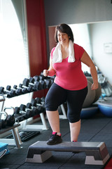 Fototapeta na wymiar Overweight woman at the gym doing fitness exercises