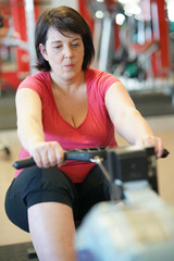 Overweight woman at the gym doing cardio exercises on rower © goodluz