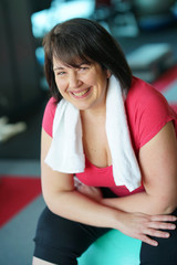 Fototapeta na wymiar Portrait of cheerful overweight woman at the gym