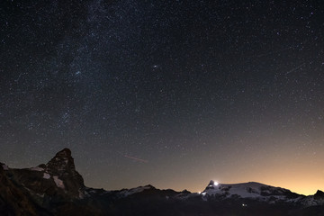 Wonderful starry sky over Matterhorn (Cervino) mountain peak and Monte Rosa glaciers, famous ski resort in Aosta Valley, Italy. Andromeda galaxy clearly visibile mid frame.