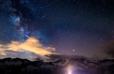 Fototapeta na wymiar The colorful glowing core of the Milky Way and the starry sky captured at high altitude in summertime on the Italian Alps, Torino Province. Mars and Saturn glowing mid frame.