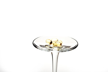 Capsules of cod-liver oil on glass stem isolated on white
