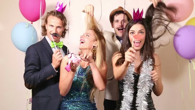 Group of beautiful friends making funny faces in party photo booth 