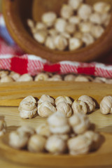 Wooden bowl with chickpeas and spoon on wooden table with red tablecloth