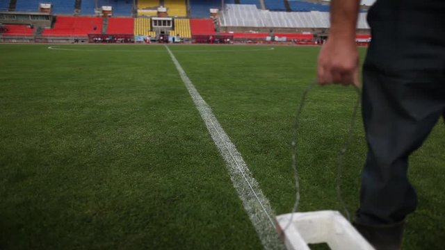 Workers put markings on a football field.
