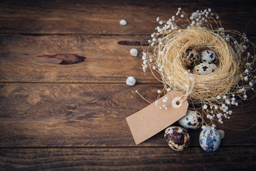 Easter quail eggs in nest over wooden background 