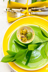  Festive table setting for Easter dinner with bright easter eggs on green plates