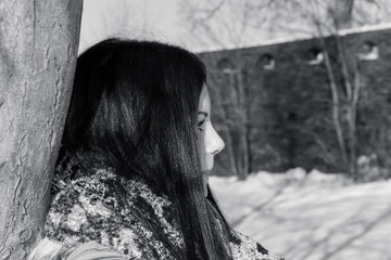 young woman leaning against a tree