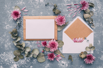 Flat lay workspace. Wedding invitation cards, craft envelopes, pink and red roses and green leaves...
