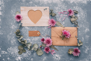 Flat lay workspace. Wedding invitation cards, craft envelopes, pink and red roses and green leaves on white background. Overhead view, top view