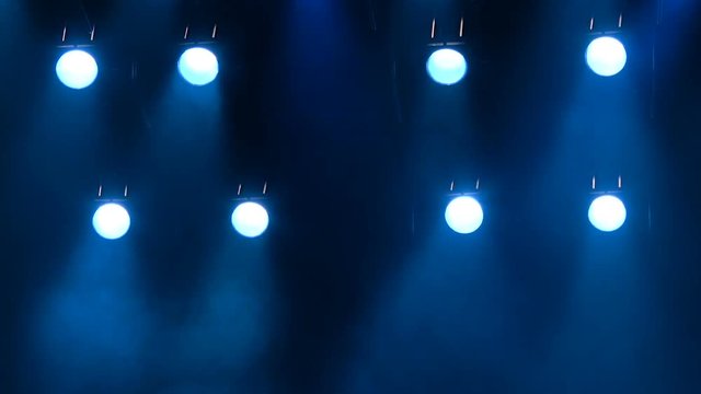 The blue light from the spotlights through the smoke on stage during a performance or show. Lighting equipment. The footage is looped without gaps.