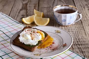 eggs pashot on a toast and tea with lemon