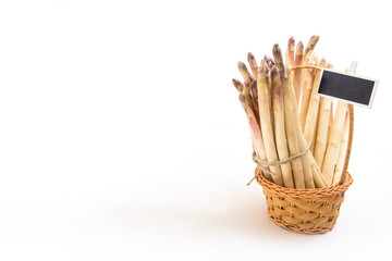 Bunch of white asparagus spears in a wicker basket, on white background and copy-space