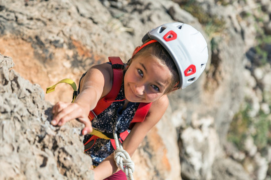 Little Child In Protective Helmet Climbing Rock