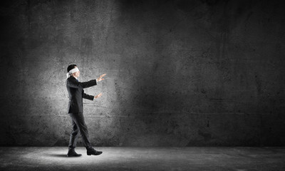 Business concept of risk with businessman wearing blindfold in empty concrete room - 141957039