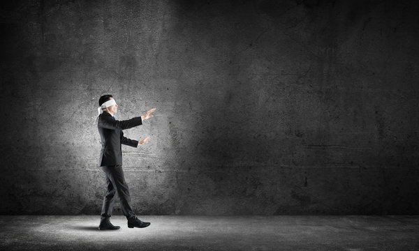 Business concept of risk with businessman wearing blindfold in empty concrete room