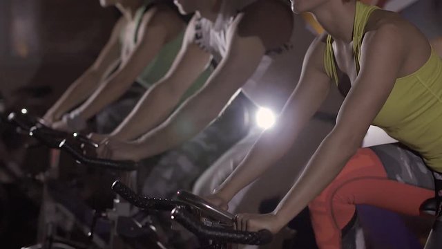 Portrait of three young people exercising on stationary bicycles in fitness club