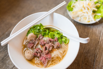 Asian Chinese noodle soup with beef and meatball fresh vegetable on wooden table delicious street food of Thailand